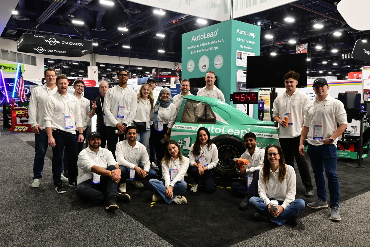 AutoLeap team in front of the branded race car at the SEMA 2025 booth