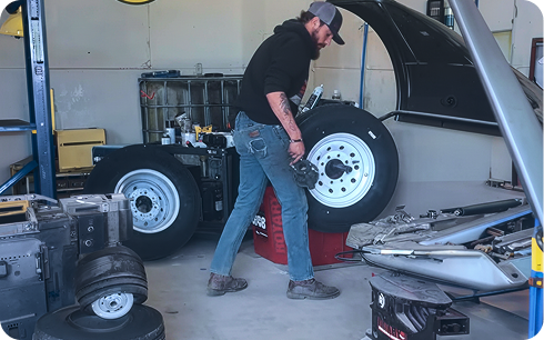 Technician at Cenla Tire & Lube moving a wheel across the shop floor
