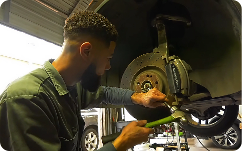 Technician at European Car Care working on the brake and wheel of a lifted vehicle