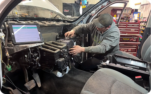 Technician at Raptor Pro Mechanics using a diagnostic scan tool inside a vehicle
