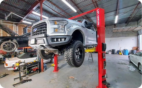 Pickup on a two-post lift inside Schimp's Garage