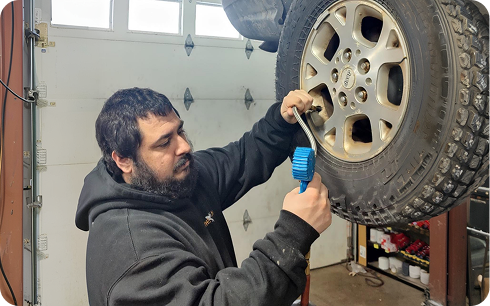 Technician inspecting a raised wheel in the bay at The Garage