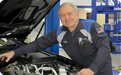 Technician at Universal Imports beside an open engine bay